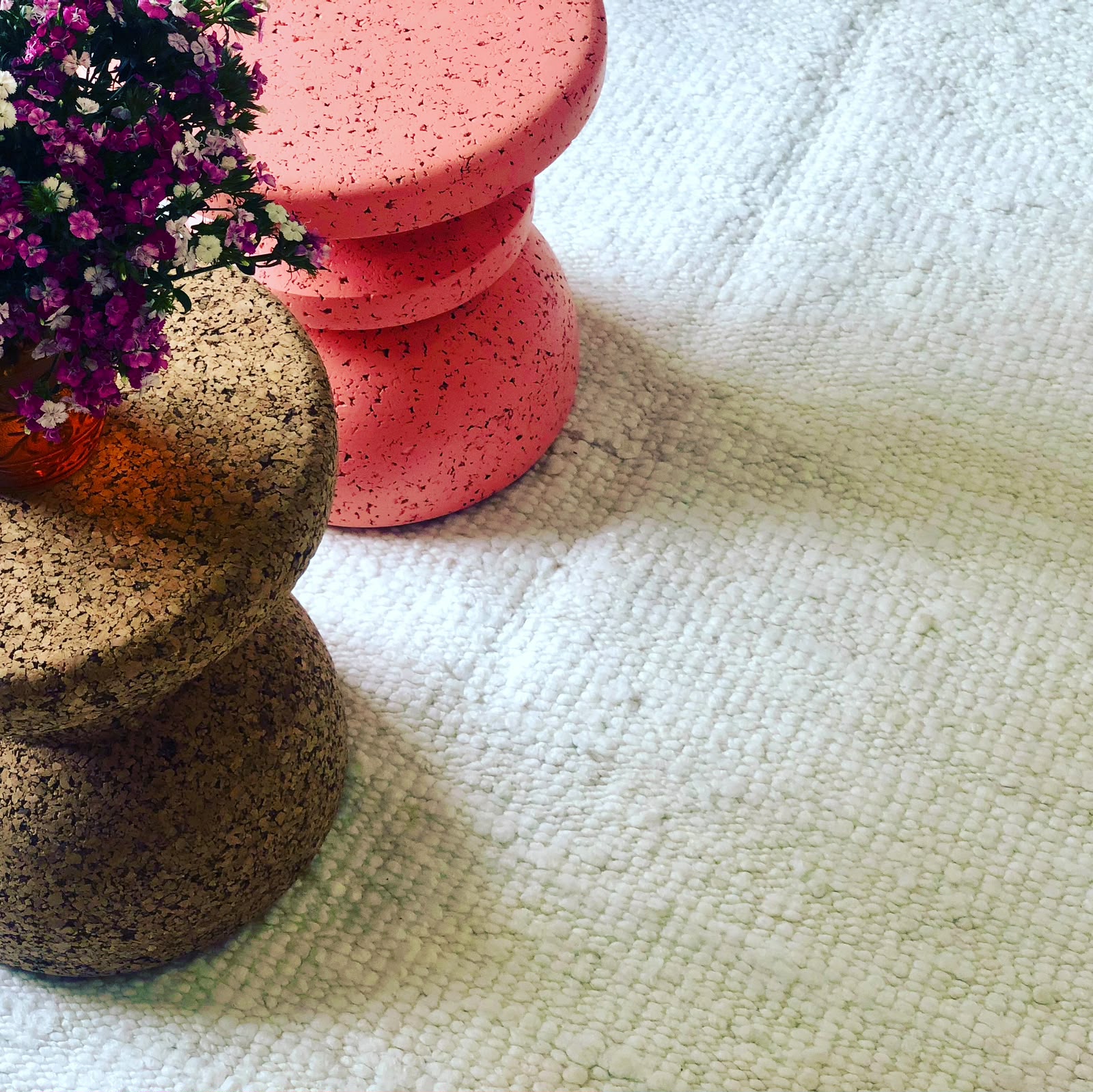 Textured beige looped Zoya rug beneath cork and pink stone stools