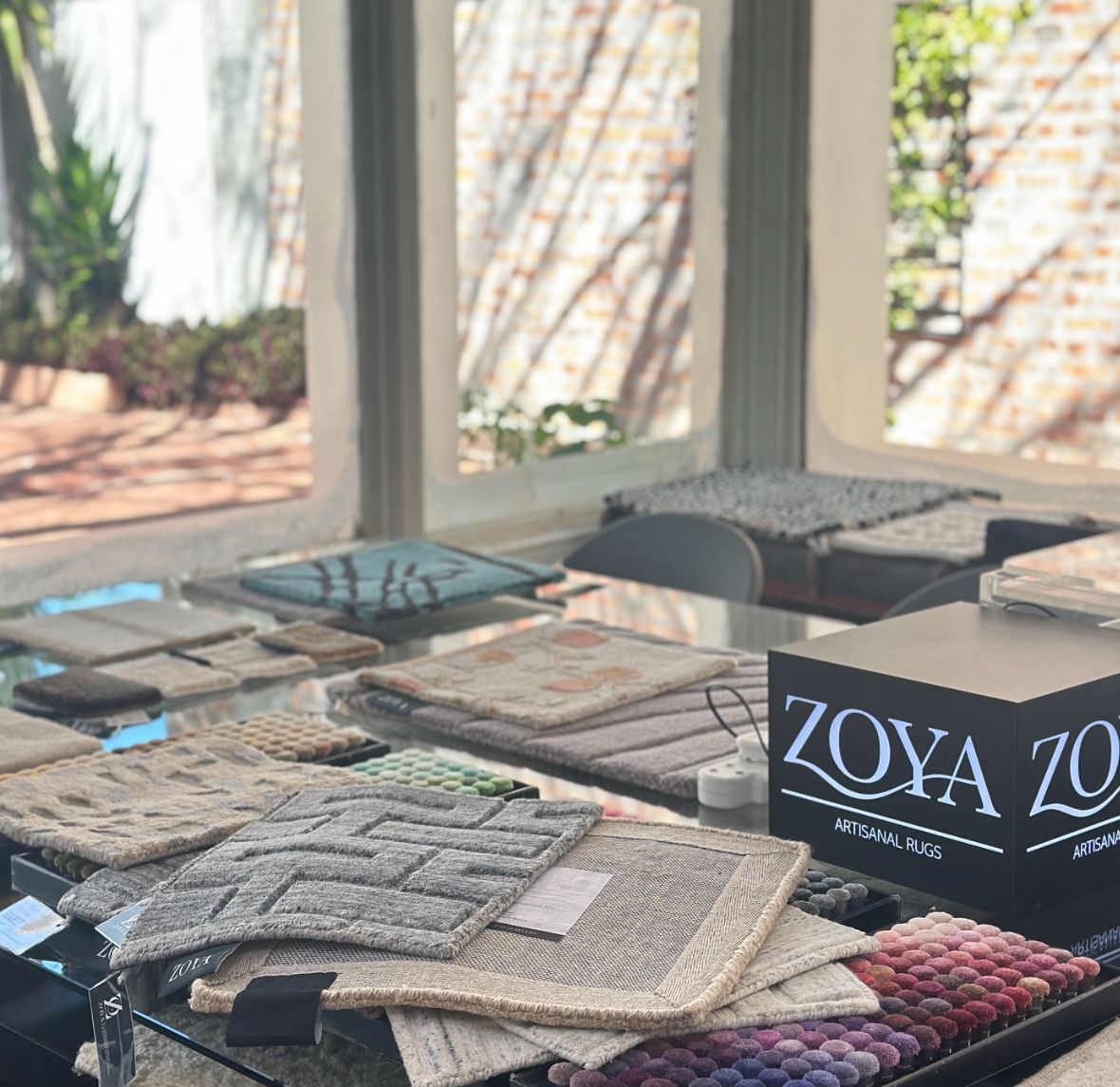 Zoya sample table with rug swatches and pom poms during a consultation