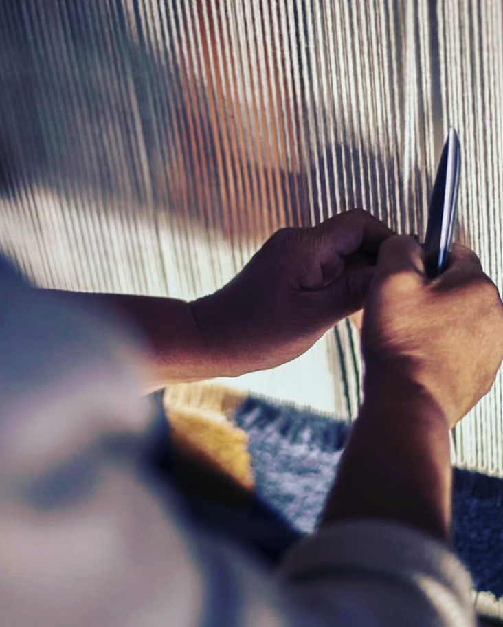 Artisan hand weaving a Zoya rug on the loom